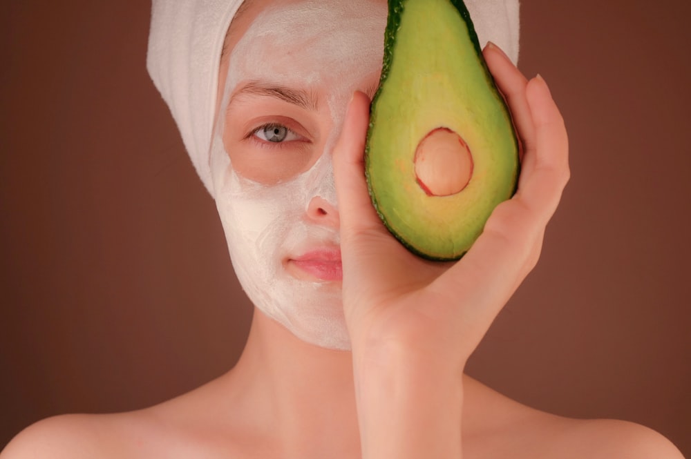 woman applying avocado paste for acne treatment at home